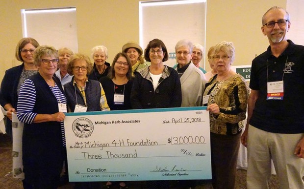 Members of Shoreline Herbarist present a ceremonial check for the Michigan 4-H Foundation to Norm Lownds, right, curator of Michigan 4-H Children's Gardens. The group helped raise funds at the convention through participating in the silent auction and herbal plant sale.