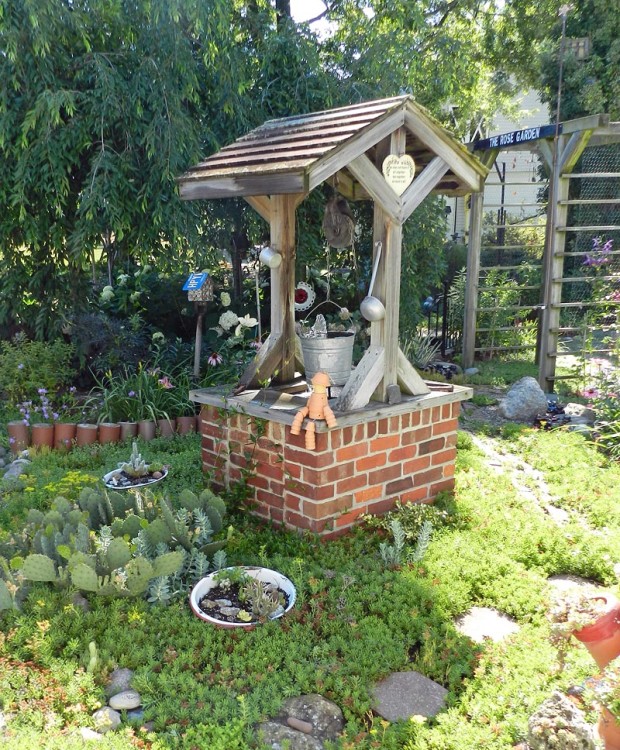 Larry made the wishing well from an old barbeque grill. The arbor Larry also made is covered with clematis, while clay drain tiles serve as a border. Insulators line the paths to keep hoses out of the gardens and prickly pear cactus (Opuntia humifusa), hardy in Michigan, surrounds a planted cactus dish garden.